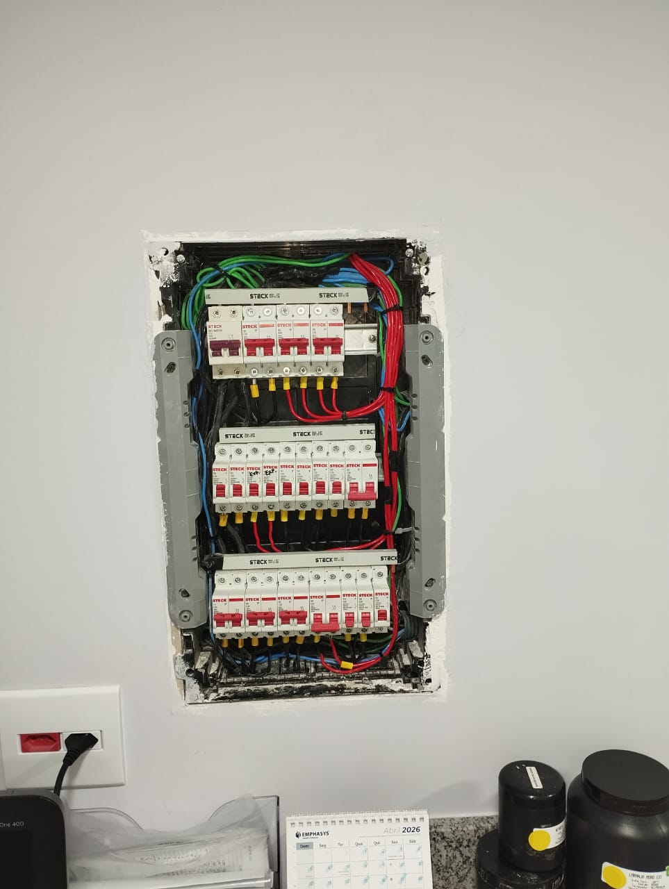 Quadro de distribuição na parede com disjuntores e fiação colorida