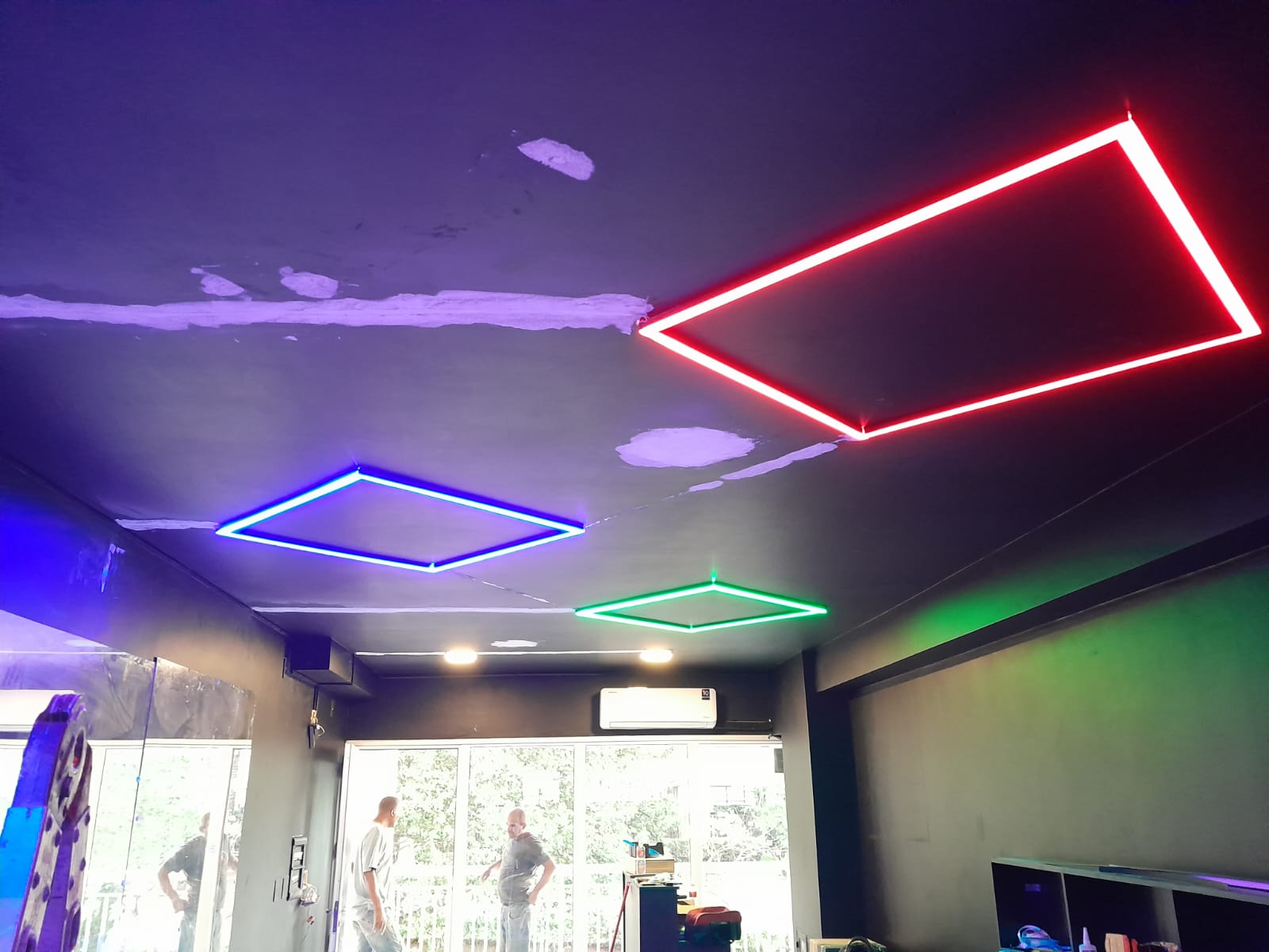 Ambiente comercial com molduras de LED em vermelho, azul e verde no teto