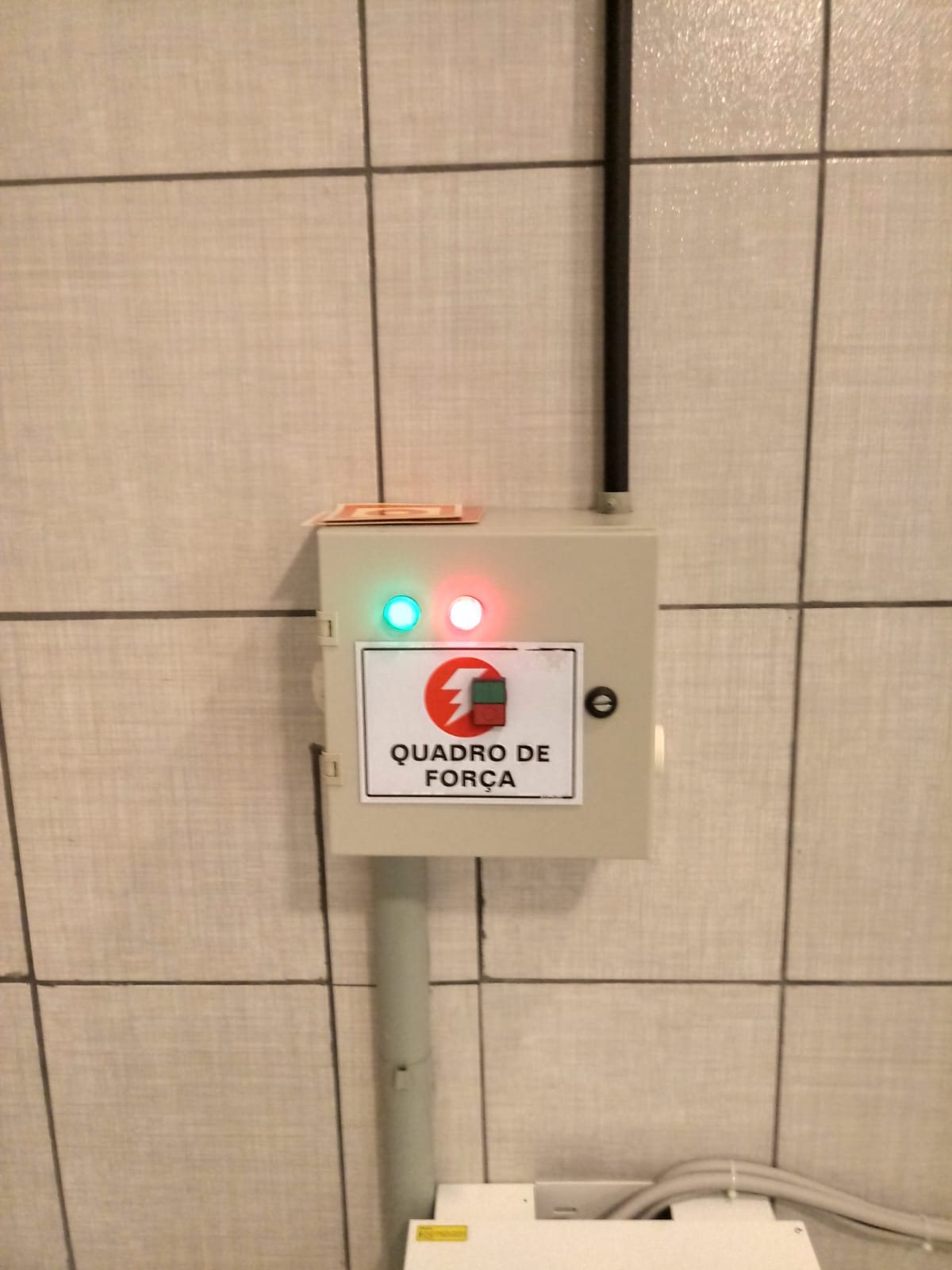 Quadro de força com sinalizadores verde e vermelho em parede de azulejo