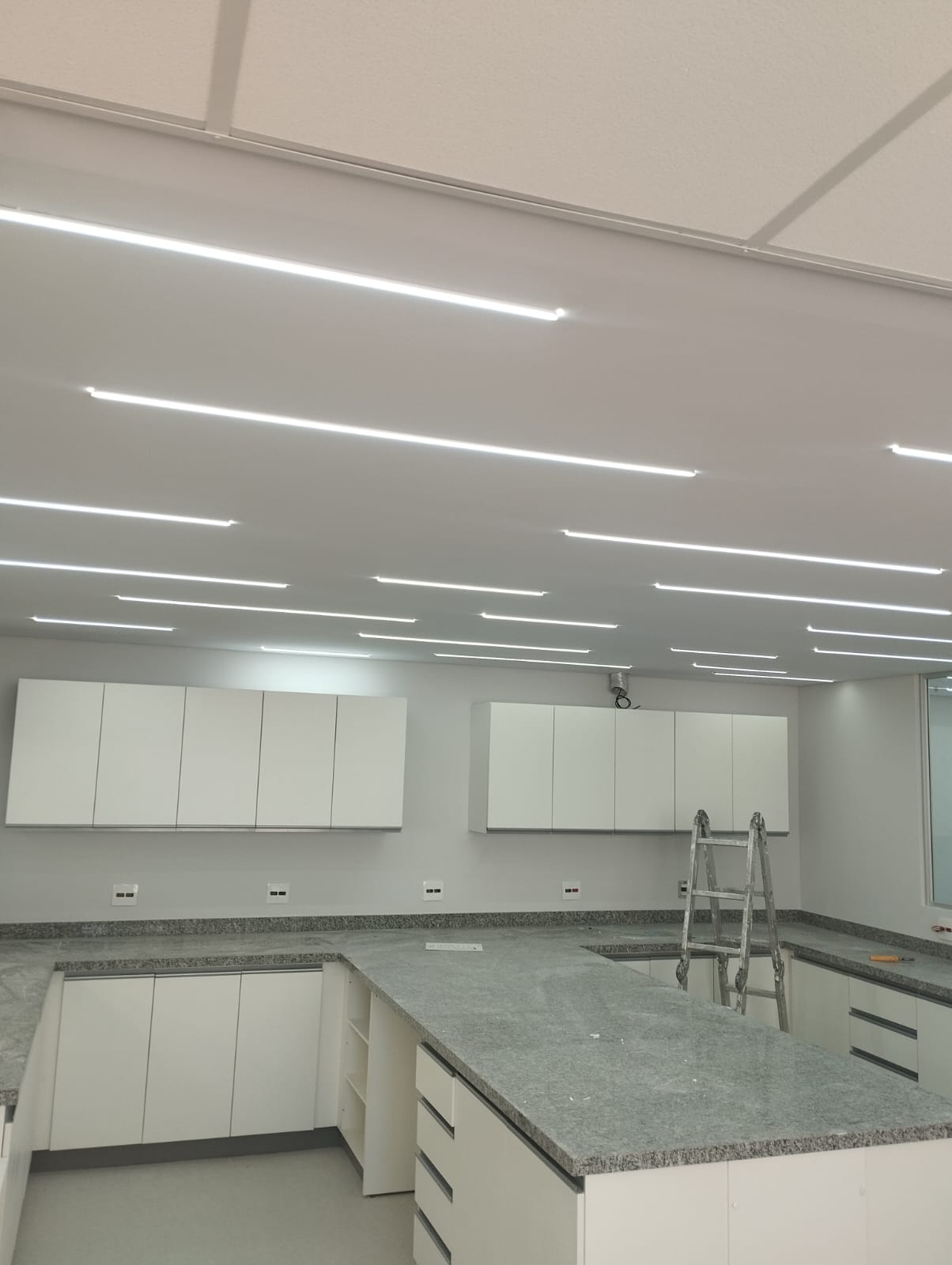 Ambiente comercial com bancadas em granito e luminárias lineares de LED no forro